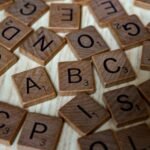 Scattered wooden Scrabble tiles showcasing letters and typography on light wooden surface.