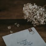 white mailing envelope beside white petaled flower